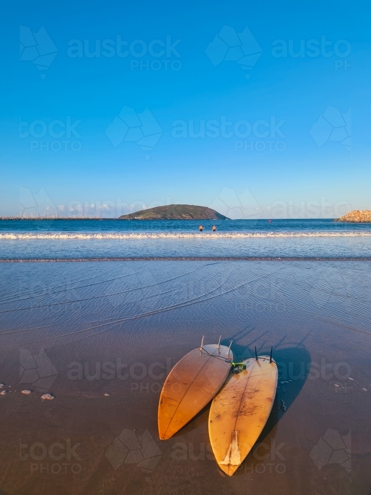 Two surfboards on the sand as the sun sets near the beach - Australian Stock Image