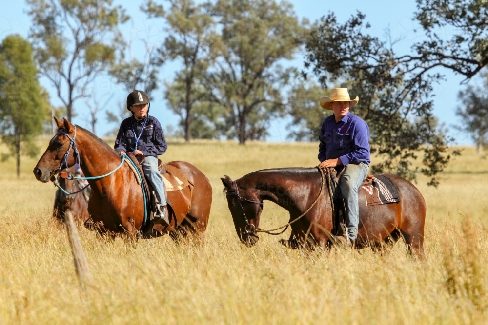 Two teenage country boys riding horses in paddock. - Australian Stock Image