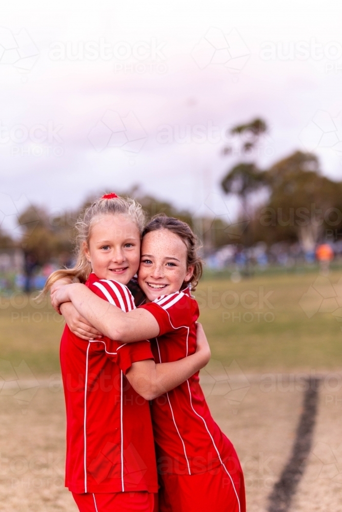 Image of Two tween football players hug at practise - Austockphoto