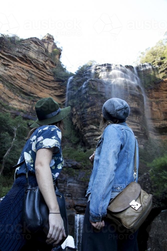 Two women looking up at waterfall - Australian Stock Image