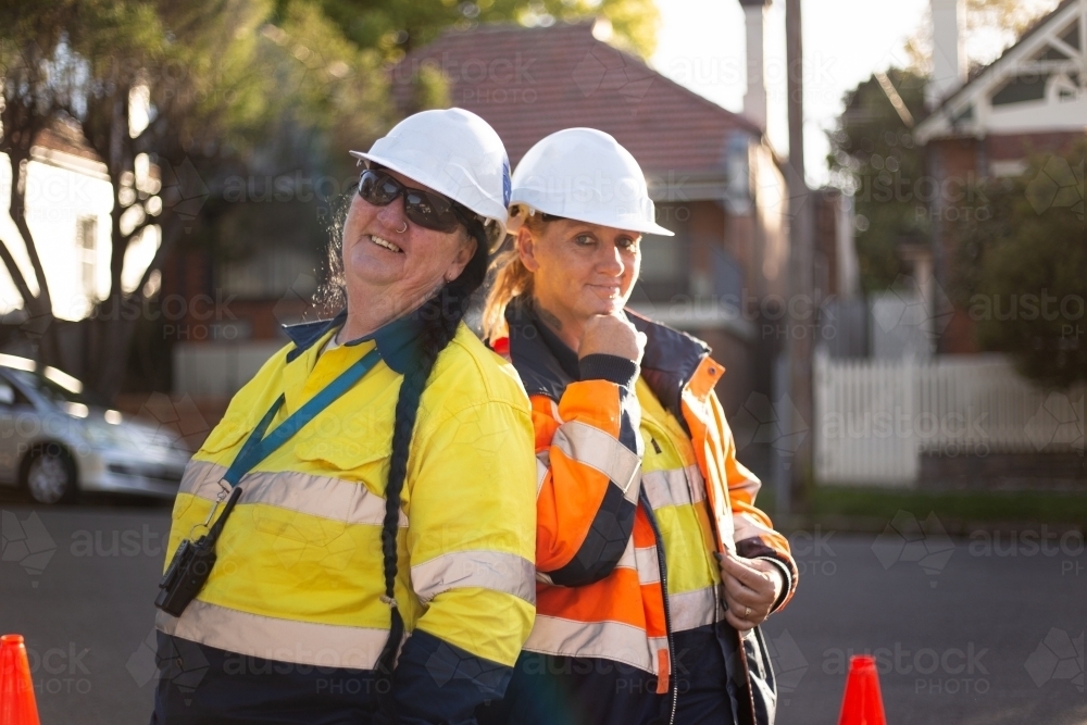 Two women road workers wearing white helmet with high vis workwear - Australian Stock Image