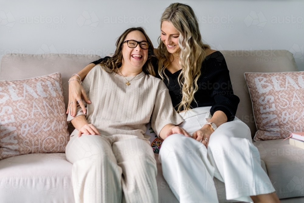 two women sitting on sofa, having a laugh. - Australian Stock Image