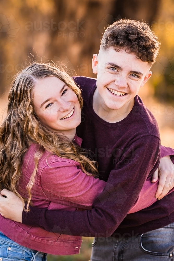 Two young adults hugging leaning forward laughing - Australian Stock Image