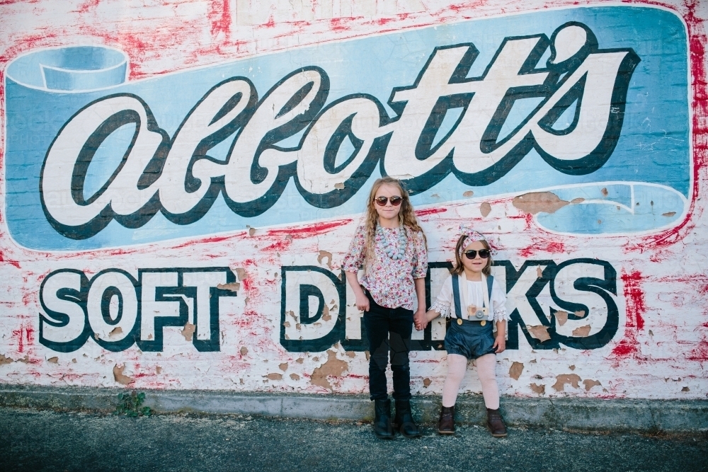 Two young fashionable urban kids with sunglasses and painted wall - Australian Stock Image