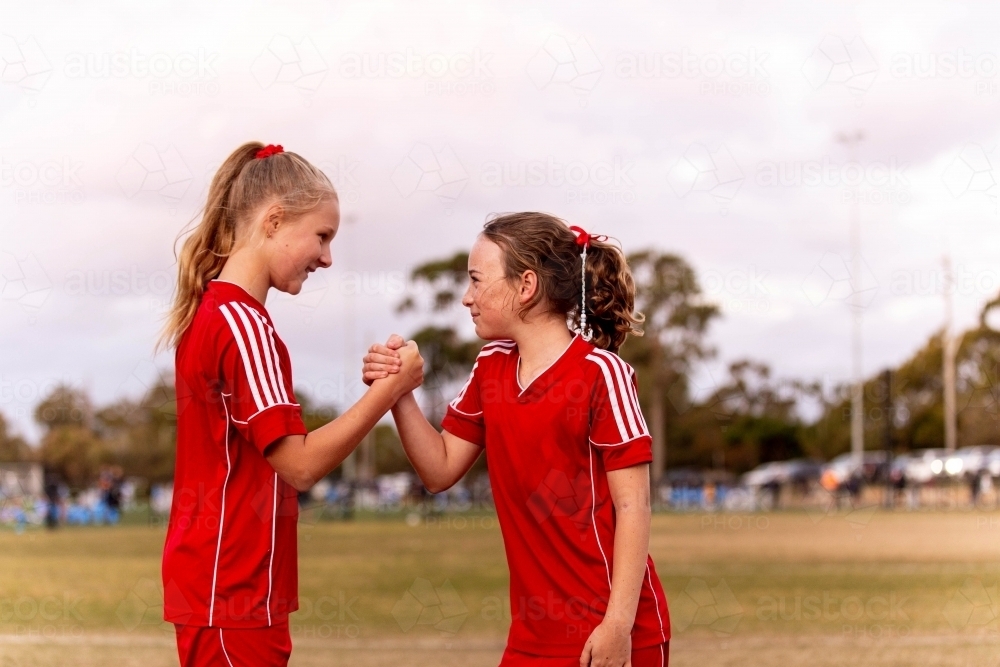 Two young female football players encouraging one another and smiling - Australian Stock Image