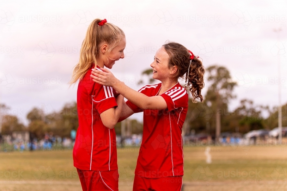 Two young female football players encouraging one another and smiling - Australian Stock Image