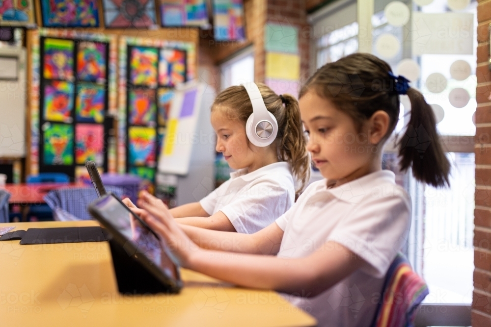 Two Young Schoolgirls on iPads in Classroom - Australian Stock Image