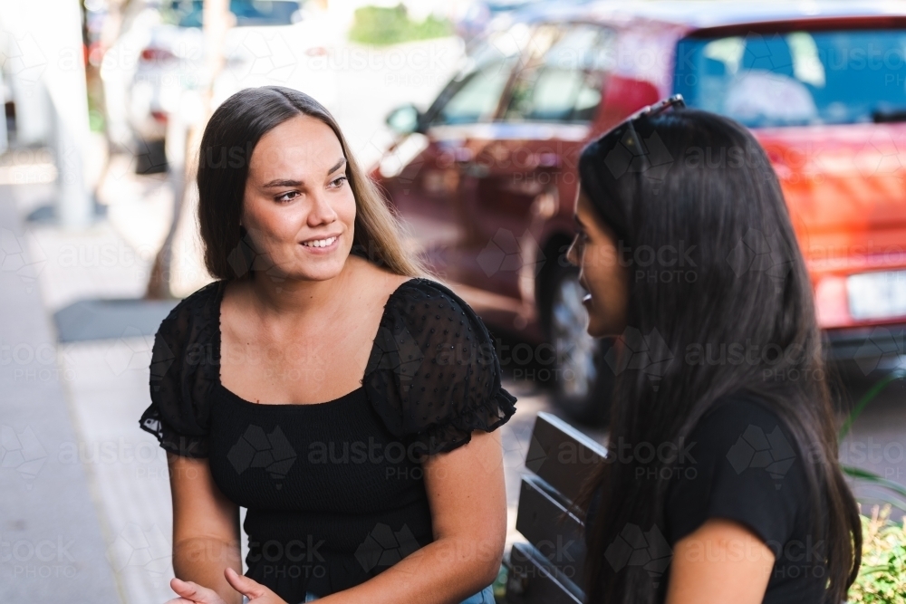 two young women sitting and talking - Australian Stock Image