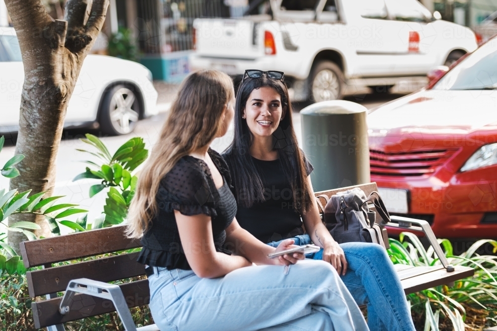 two young women sitting and talking - Australian Stock Image