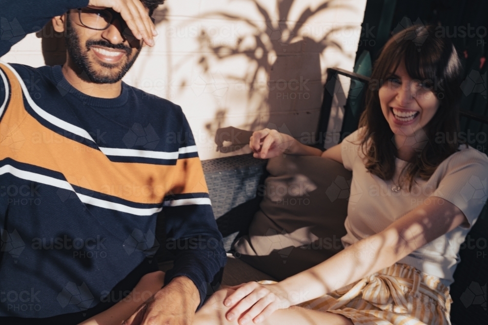 UGC style, couple sitting outside in the sun on their house veranda - Australian Stock Image