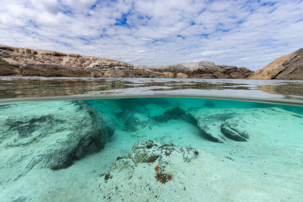 Under-over underwater ocean rock pool scene showing starfish on a pristine, wild coastline - Australian Stock Image