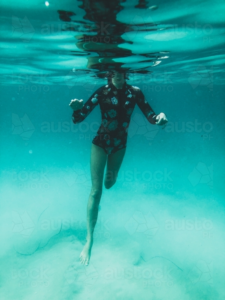 Underwater of Female body treading water in ocean wearing full piece swimsuit - Australian Stock Image