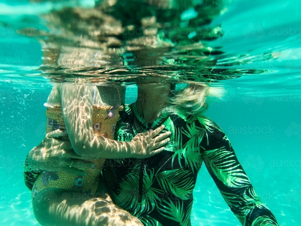 Underwater view of Woman holding young girl - Australian Stock Image