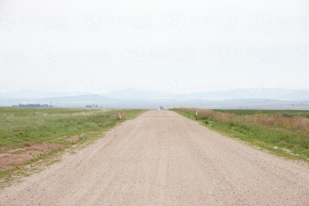 Unsealed gravel road through farmland paddocks - Australian Stock Image