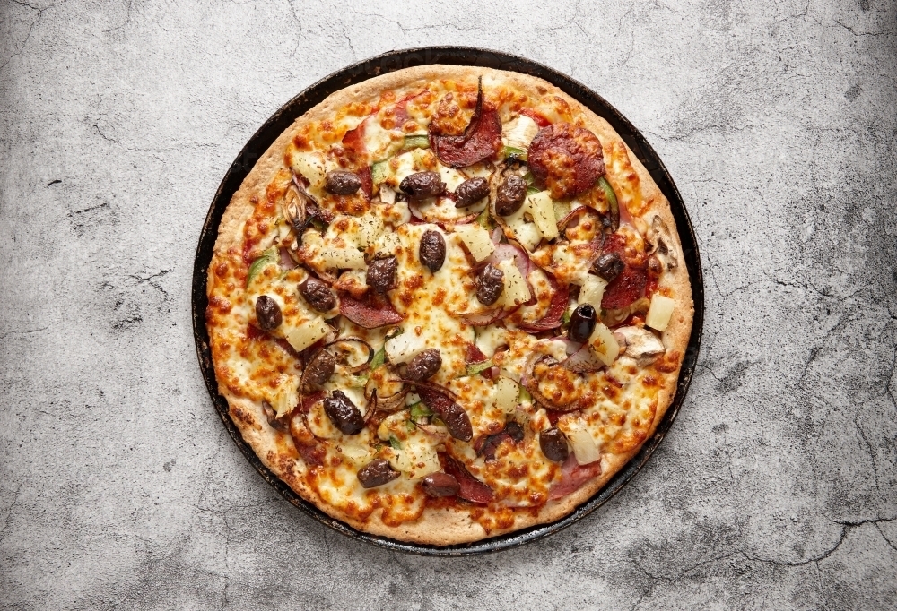 Unsliced pizza on a black pan - Australian Stock Image