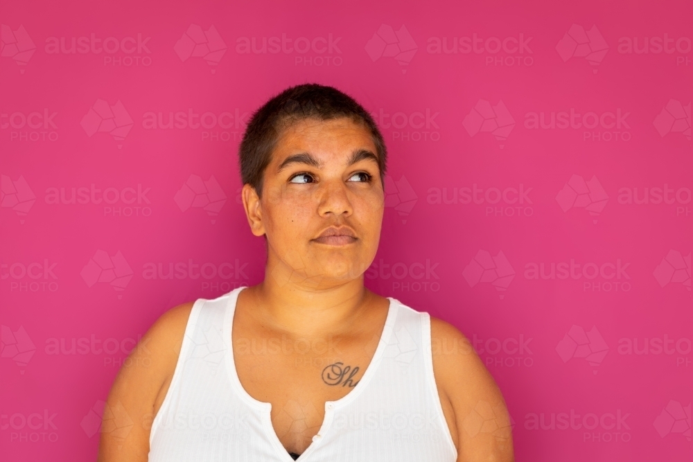 upper body of woman with very short hair against magenta backdrop - Australian Stock Image