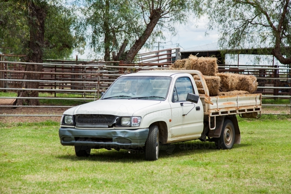 Ute loaded with hay bales driving on farm - Australian Stock Image