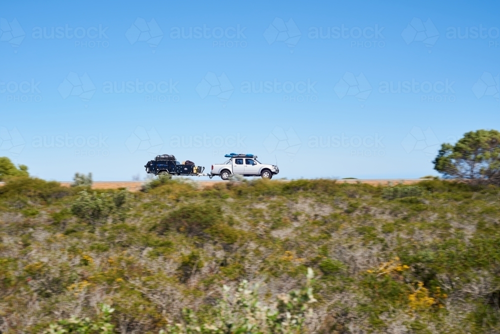 Ute towing a camper trailer on a road trip in coastal Western Australia, with motion blur. - Australian Stock Image