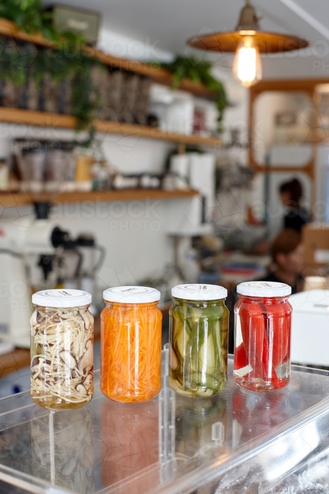 Variety of pickle jars lined up on counter in cafe - Australian Stock Image