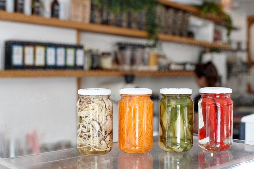 Variety of pickle jars lined up on counter in cafe - Australian Stock Image