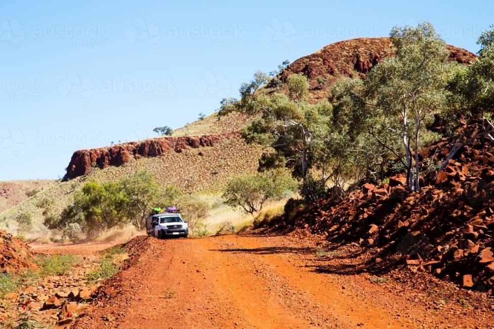 vehicle travelling on dirt road through rugged hills - Australian Stock Image