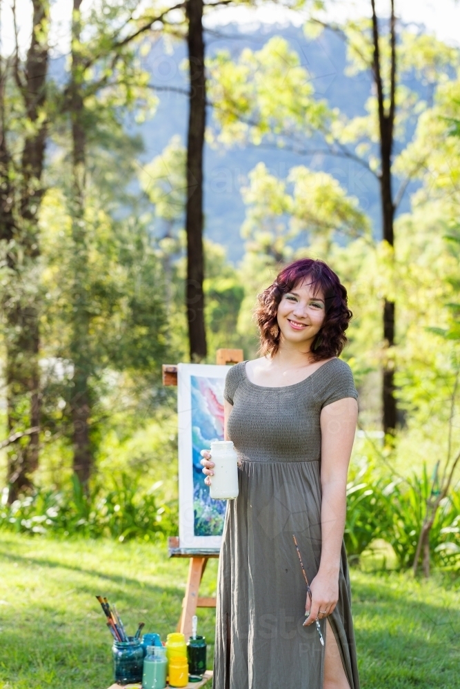 Vertical image of happy young woman smiling holding paint pot - Australian Stock Image