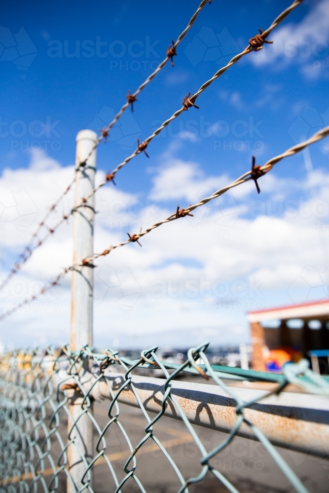 vertical photo of a fence with barbed wire on top - Australian Stock Image