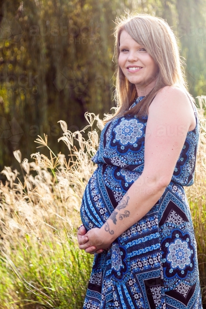 Vertical portrait of happy pregnant mother outside - Australian Stock Image