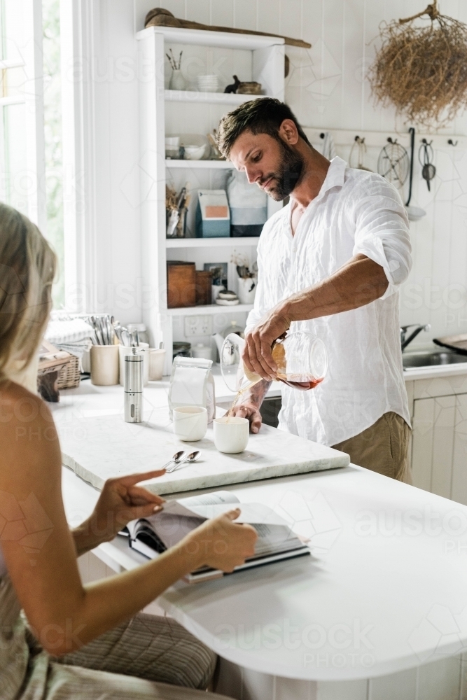 Vertical shot of a man pouring coffee on a white cup - Australian Stock Image