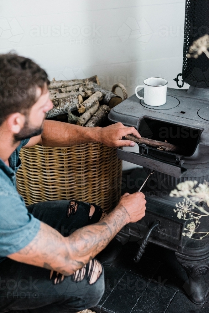 vertical shot of a man preparing a wood stove - Australian Stock Image