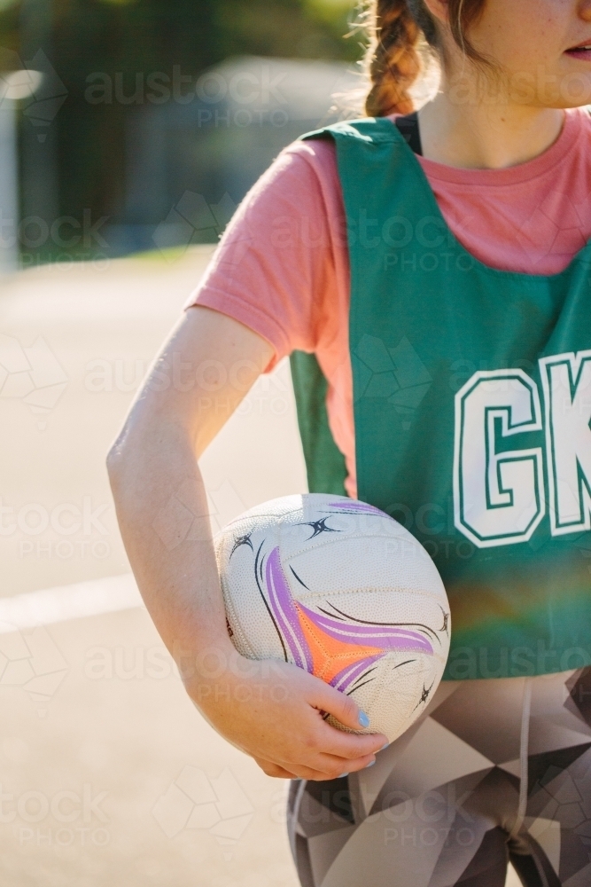 vertical shot of a young woman in sports wear holding a net ball in between her hands and her waist - Australian Stock Image