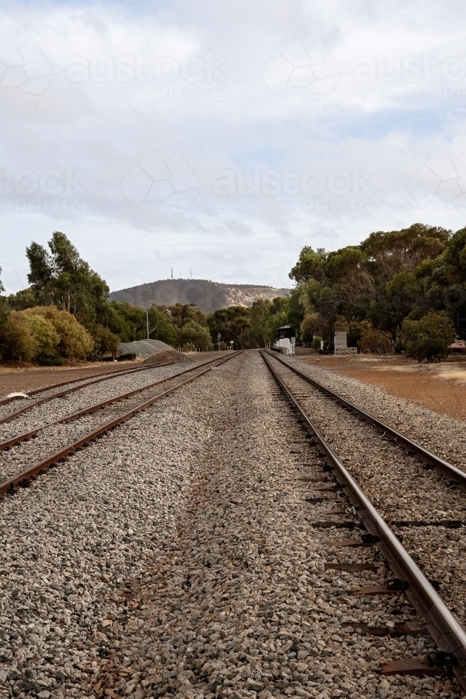 Vertical view looking along railway tracks leading out of country town - Australian Stock Image