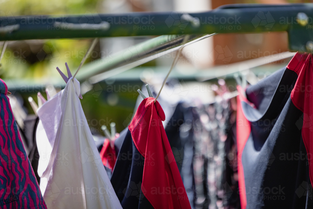 Vibrant clothes drying on a line in the sun, showcasing diverse patterns and fabrics - Australian Stock Image