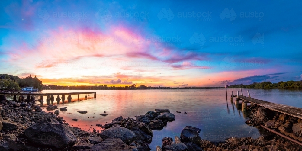 Vibrant colours of dawn, before sunrise, above a pier on Tweed River - Australian Stock Image