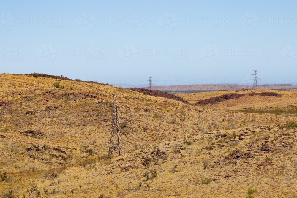 view across the barren pilbara landscape featuring high-tensile power lines - Australian Stock Image