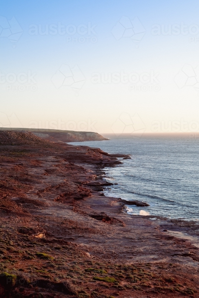 View along coastal rocky cliffs at sunset - Australian Stock Image