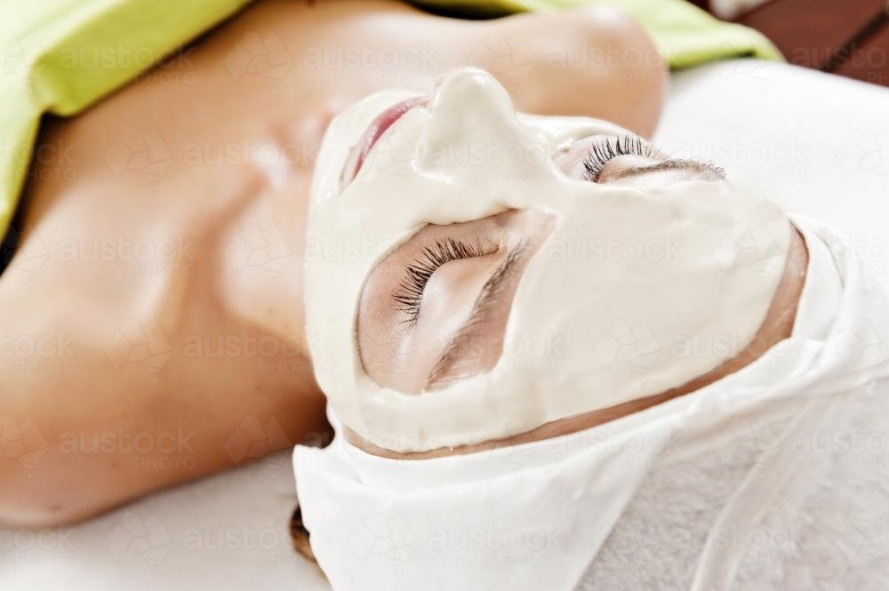 view from behind of a woman with a facial mask during a beauty treatment - Australian Stock Image