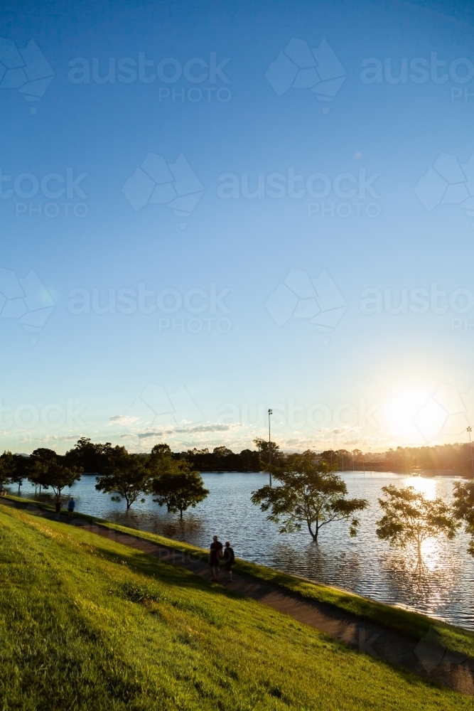 View of sunlight shining off water during flood as it rises up the levee bank - Australian Stock Image