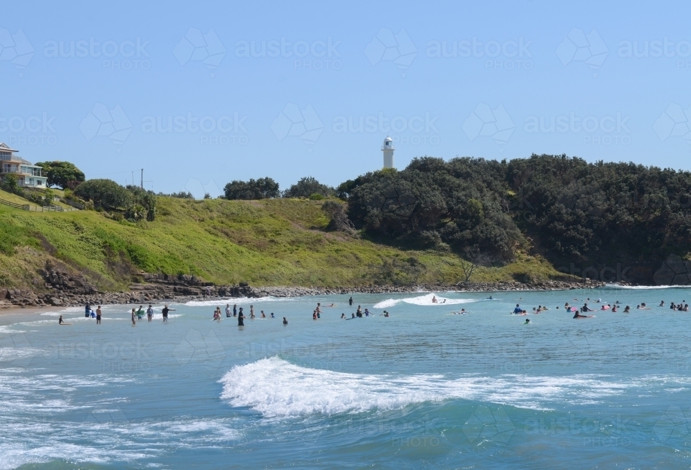 View of swimmers at Main Beach, Yamba, with lighthouse in background - Australian Stock Image