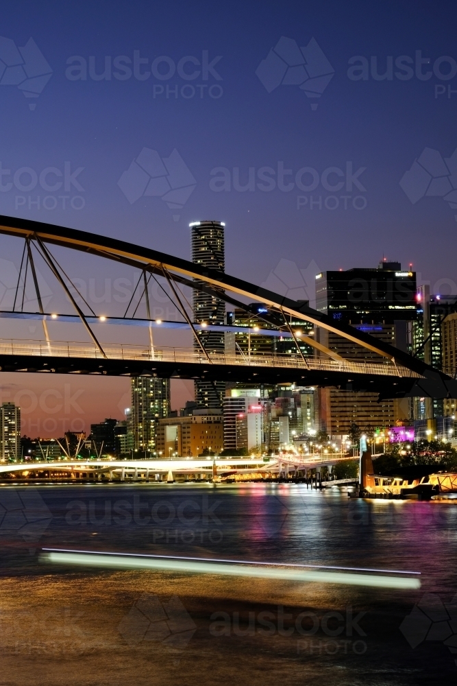 View of the Brisbane River at dusk with the Goodwill Bridge and lights from a passing ferry - Australian Stock Image