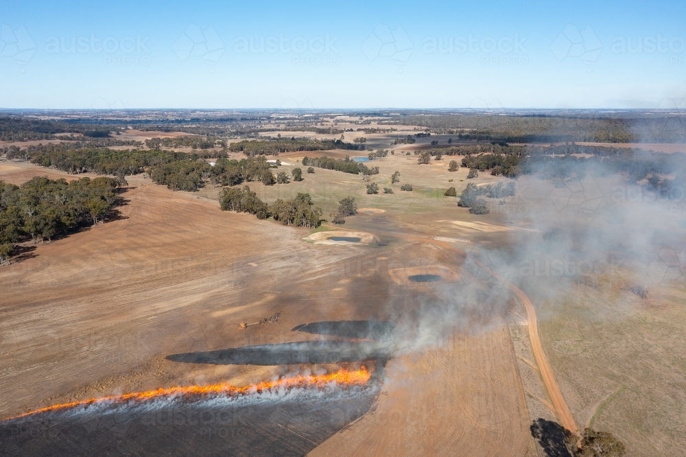 view over farmland with stubble burn sending smoke into the air - Australian Stock Image