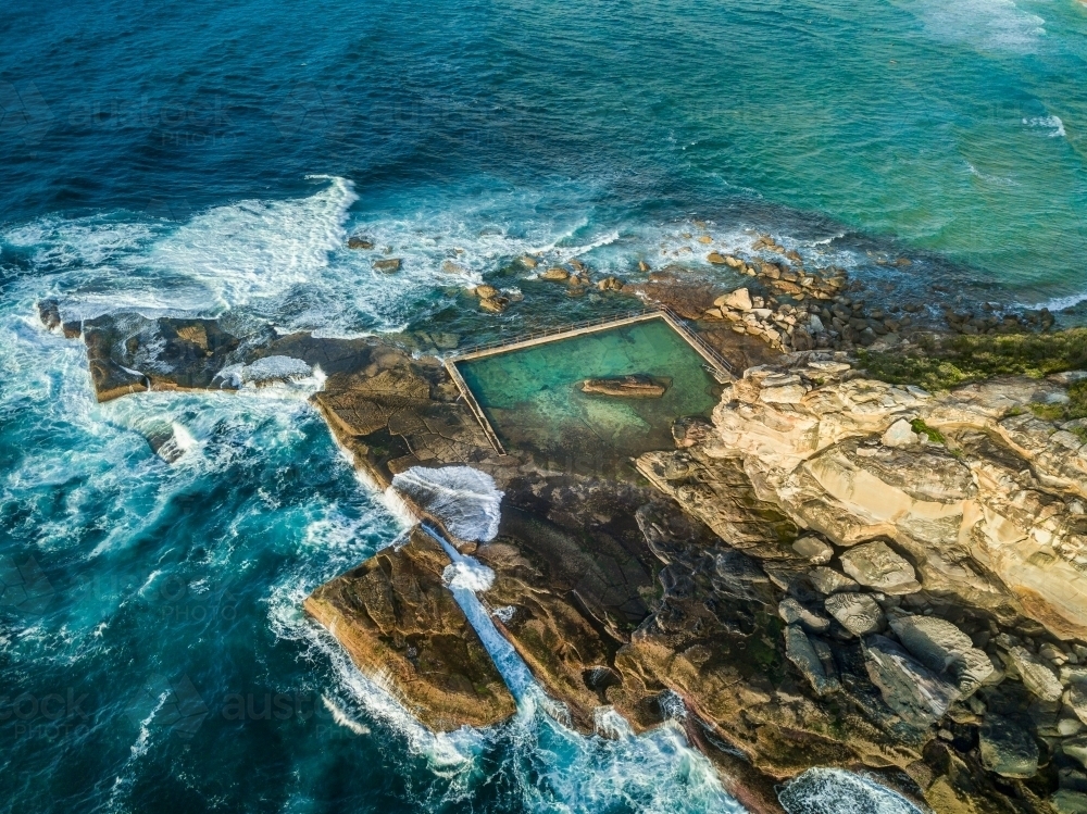 Views of the rockpool as it sits nestled at the bottom of the cliffs surrounded by ocean - Australian Stock Image