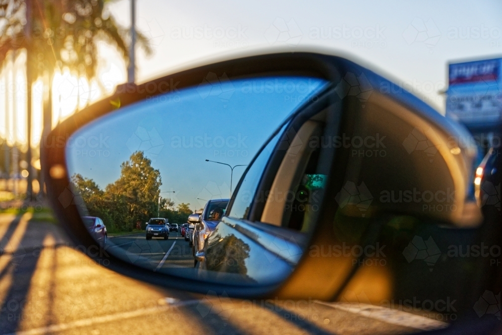 Watching traffic behind looking through the side mirror at sunset golden hour - Australian Stock Image