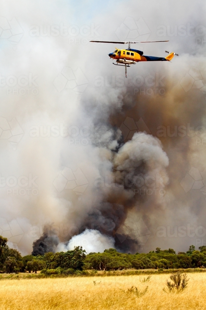 Water-bombing helicopter among thick smoke. - Australian Stock Image