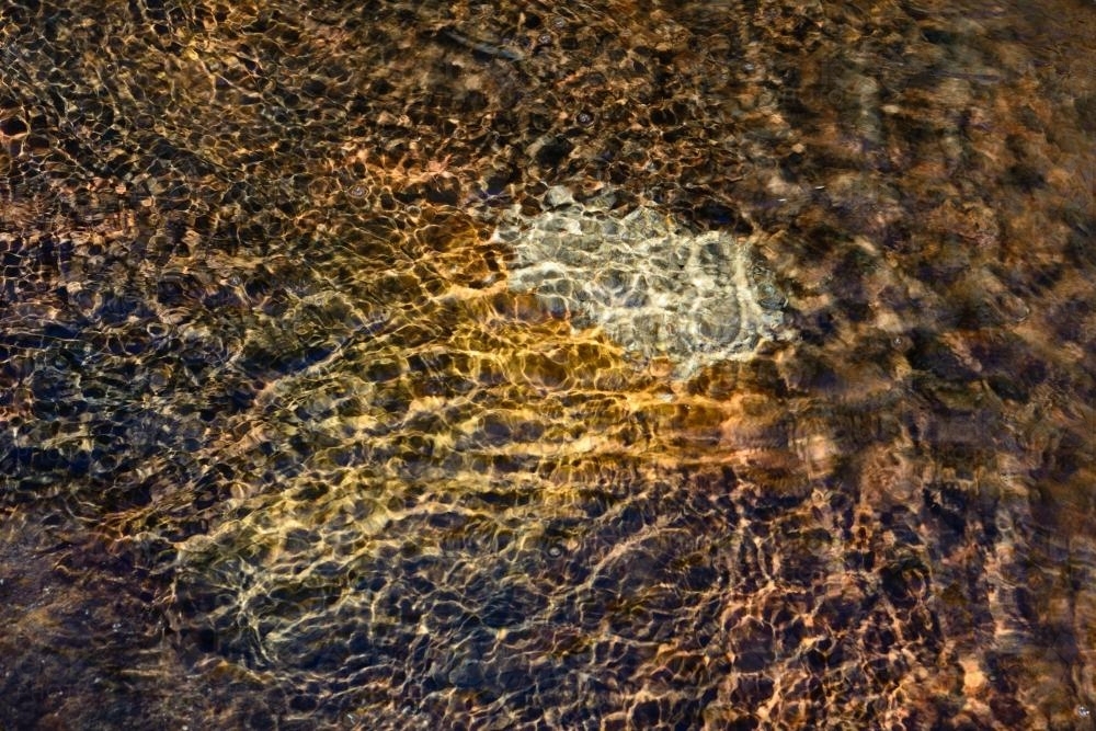 Water rippling over colourful sandstone - Australian Stock Image