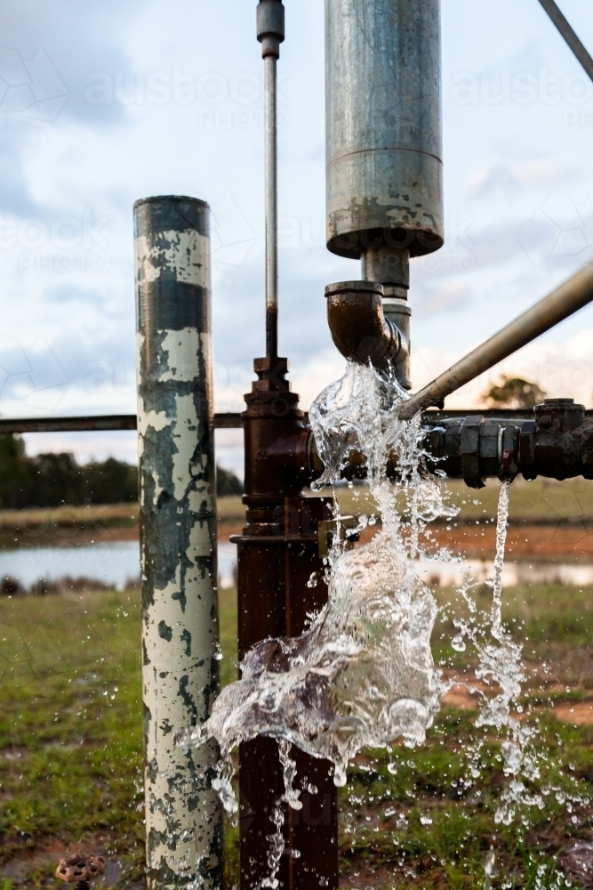 Water splashing from windmill pump on farm - Australian Stock Image