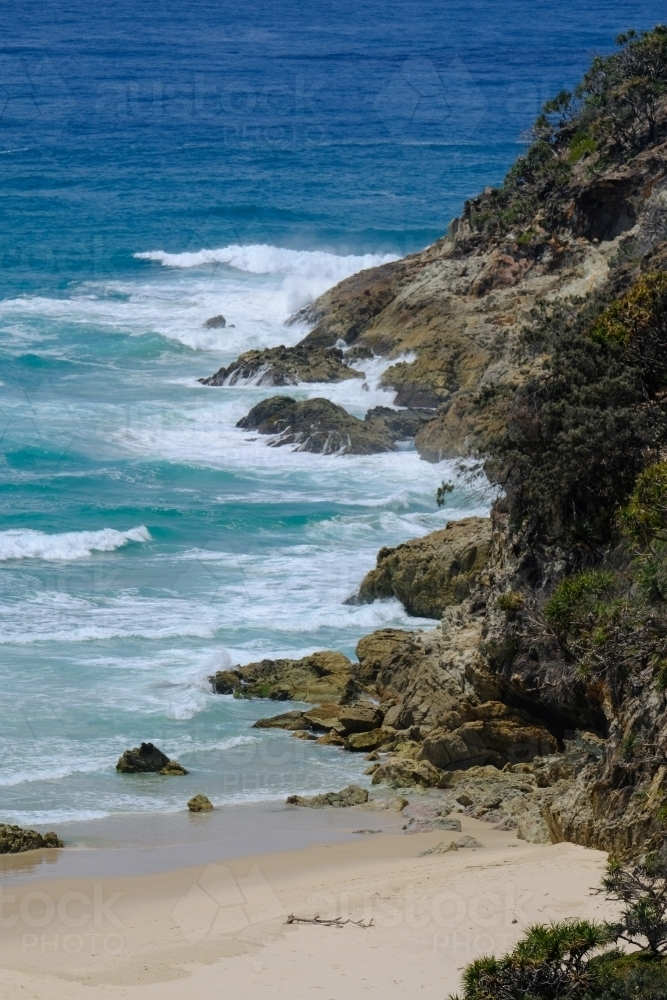 Water washing against sand and rocky cliffs of Deadman's Beach - Australian Stock Image