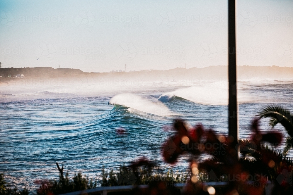 Waves crashing coastline at sunrise with sea spray - Australian Stock Image