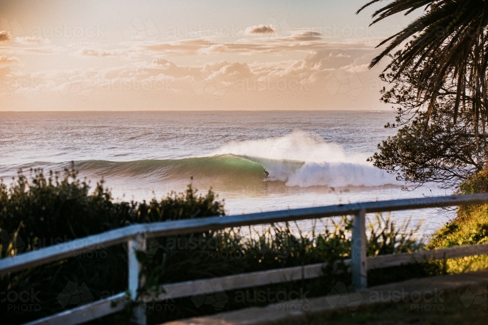 Waves crashing coastline at sunrise with sea spray - Australian Stock Image