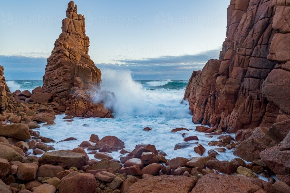 Waves crashing on a rocks along a coastline covered with large boulders and rock formations - Australian Stock Image